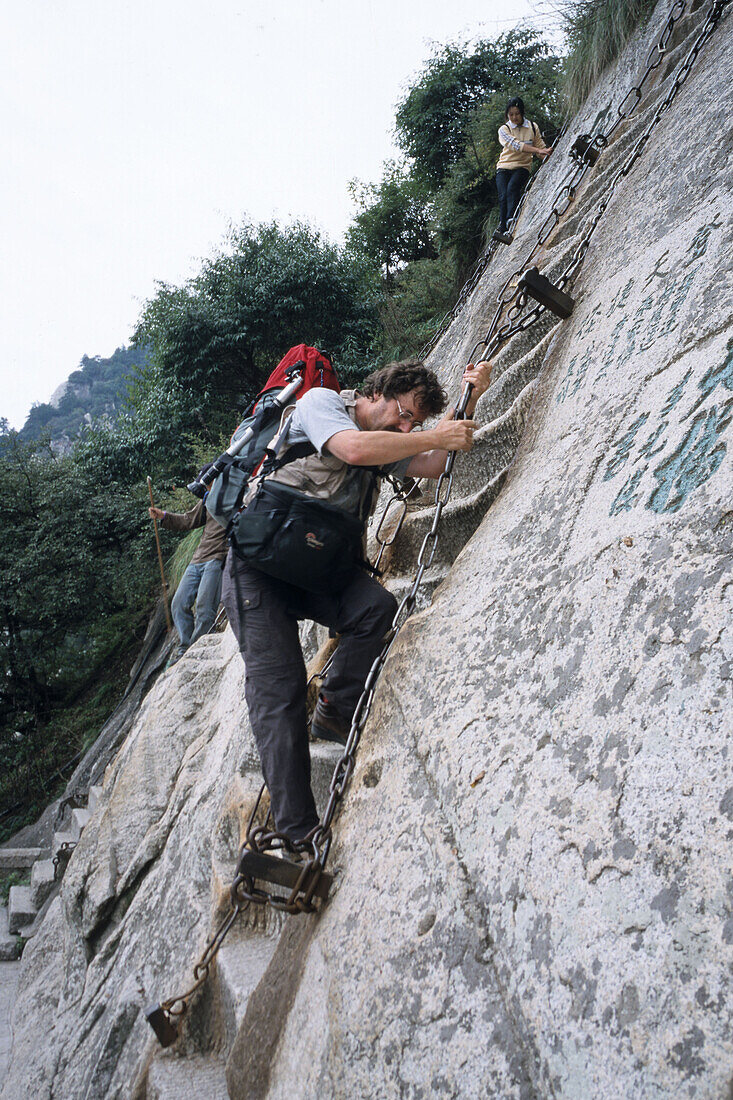 photographer Karl Johaentges with backpack and camera bag, vertical stone cliffs, Taoist mountain, Hua Shan, Shaanxi province, Taoist mountain, China, Asia