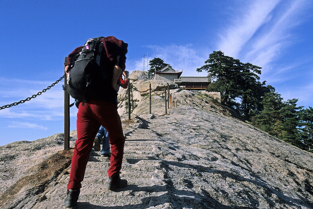 Fish Back Ridge, pilgrim path along stone steps with worn down chain handrail to South Peak Monastery, western tourist with backpack, Hua Shan, Shaanxi province, Taoist mountain, China, Asia