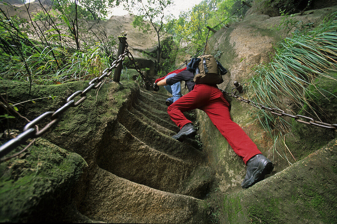 western tourist on steep pilgrim path along stone steps with worn down chain handrail, Hua Shan, Shaanxi province, Taoist mountain, China, Asia