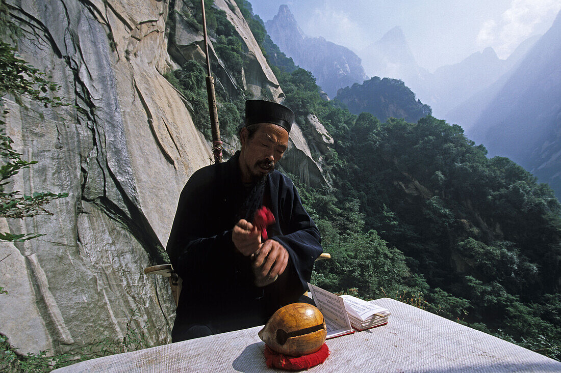 Taoist hermit monk prays in front of his hut, cliff, Hua Shan, Shaanxi province, Taoist mountain, China, Asia