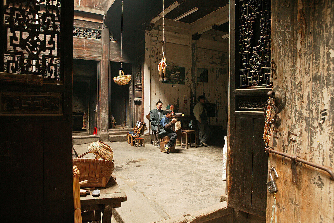 Menschen in einem Innenhof mit geschnitzten Holzwänden, Hongcun, Huangshan, China, Asien