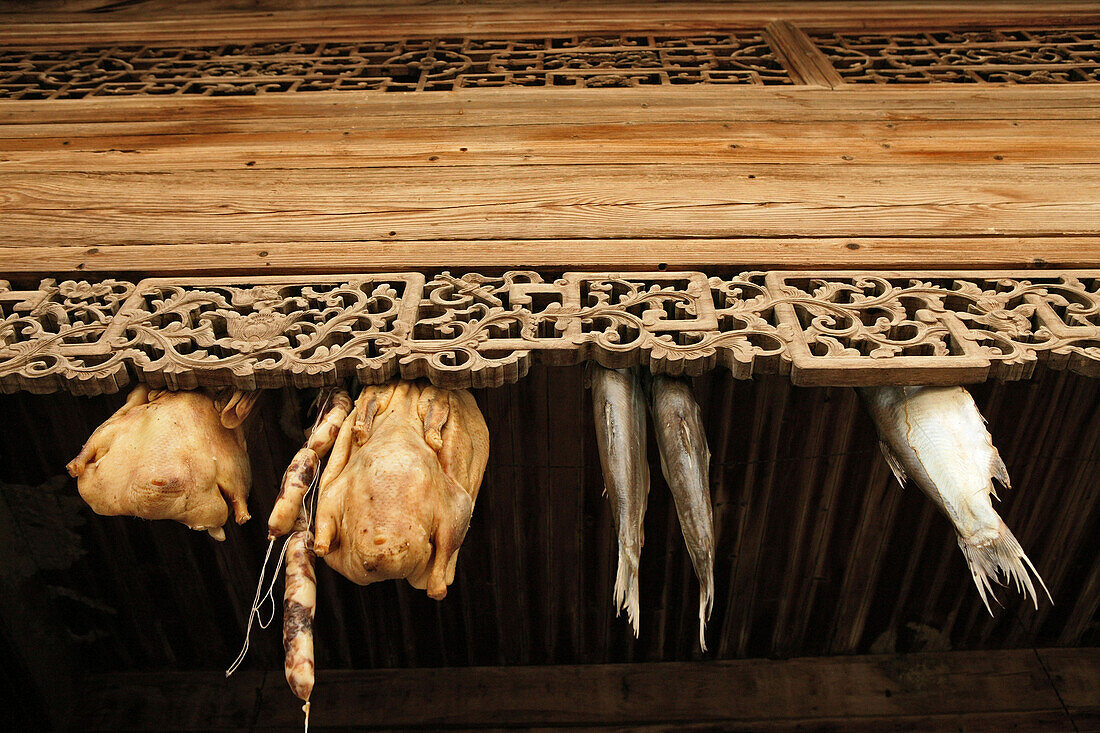 Kunstvolle Schnitzereien und getrocknete Lebensmittel an den Dachbalken eines Hauses in Hongcun, Huang Shan, China, Asien