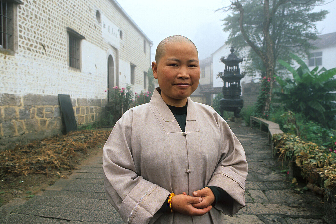 A nun standing in front of monastery of the village minyuan, Jiuhua Shan, Anhui province, China, Asia