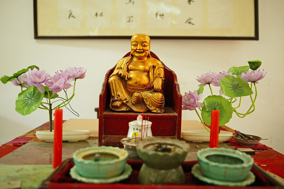 dining hall altar with Buddha statue and plastic lotus flowers, Jiuhua Shan Village, Monastery, Jiuhuashan, Mount Jiuhua, mountain of nine flowers, Jiuhua Shan, Anhui province, China, Asia