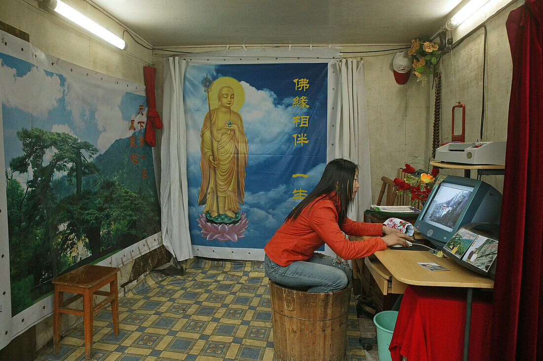 Junge Frau sitzt in einem Fotostudio auf einem Fusswärmer Huo Tong, Jiuhua Shan, Provinz Anhui, China, Asien