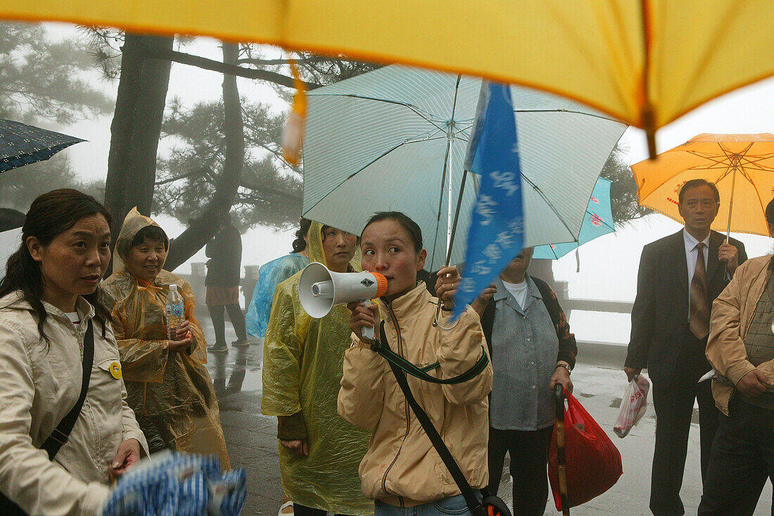 A group of pilgrims standing in the rain, Jiuhua Shan, Anhui province, China, Asia