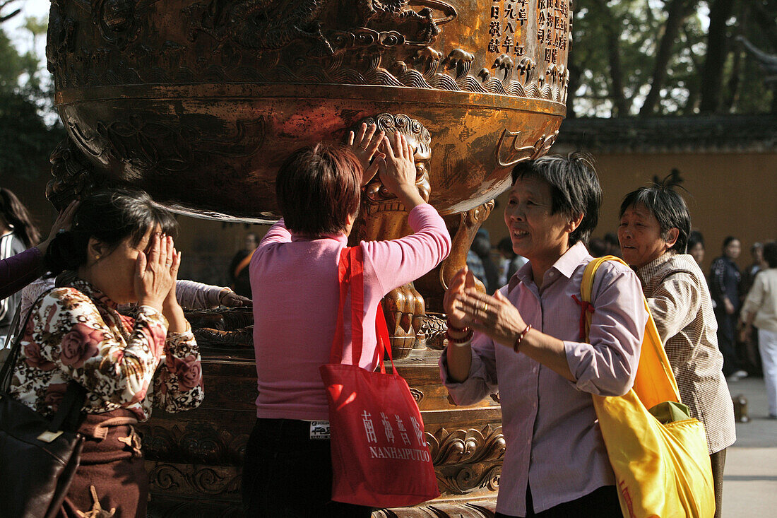 pilgrims touch bronze cauldron, hope for healing energy, Fayu Monastery on the Buddhist Island of Putuo Shan near Shanghai, Zhejiang Province, East China Sea, China, Asia