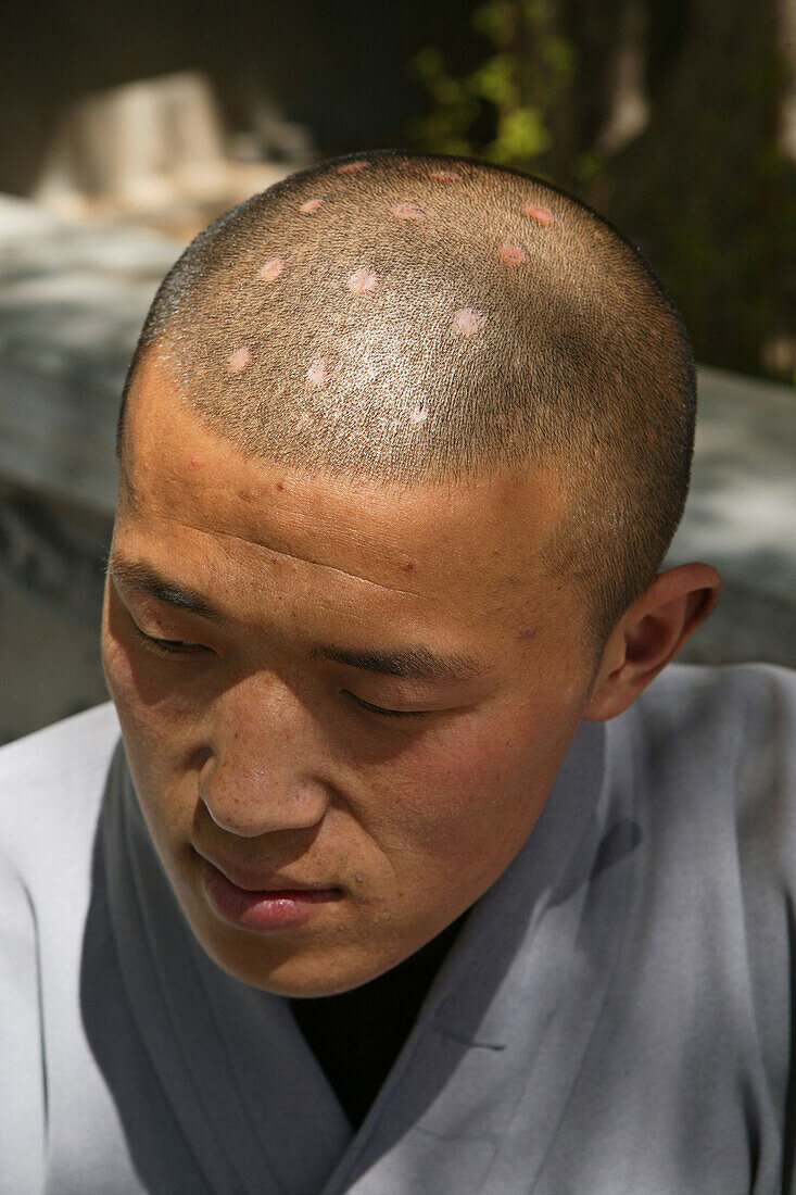 Shaolin monk with symbolic burn marks on his shaven head, Shaolin Monastery, known for Shaolin boxing, Taoist Buddhist mountain, Song Shan, Henan province, China