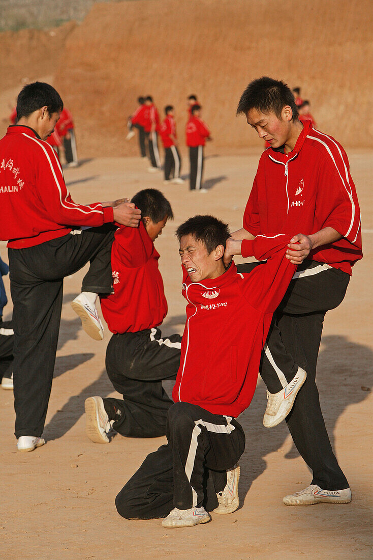 Kungfu Training, Schule, Song Shan,Kungfu Morgenübung, Dehnungsübung einer Kungfu Klasse neben dem Shaolin Kloster, Traingsanzug rot, Songshan, Provinz Henan, China, Asien