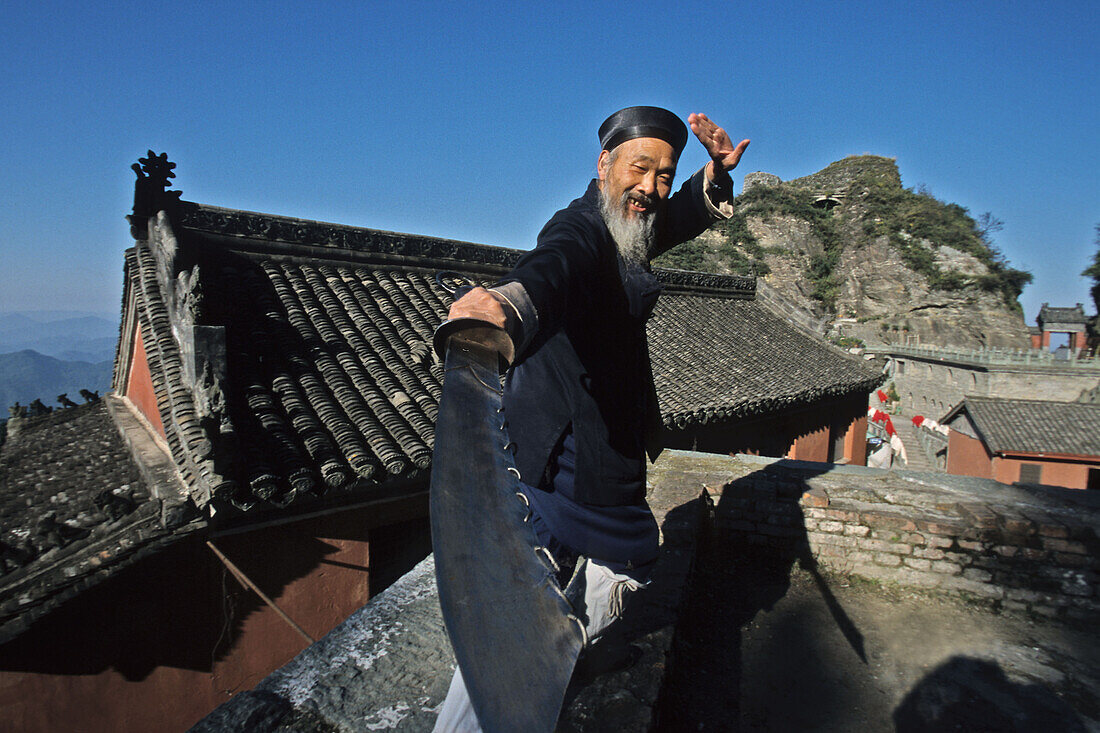 Klosterstadt, ritueller Schwertkampf, Wudang Shan,Taichi Meister und Mönch demonstriert rituellen Schwertkampf, Klosterstadt Tian Zhu Feng, rot getünchte Klosterbauten, Gipfel des Wudang Shan, daoistischer Berg in der Provinz Hubei, Geburtsort des Taichi,