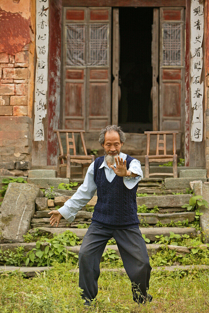 Taichi Meister, Wudang Shan,Taichi Meister, demonstriert Taiji Zyklus vor seinem alten Haus am Fuß des Wudang Shan, daoistischer Berg in der Provinz Hubei, Geburtsort des Taichi, China, Asien, UNESCO Weltkulturerbe