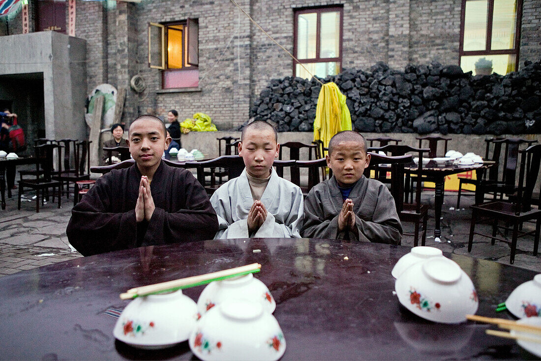 Junge Mönche beim Mittagessen, Kohlenlager im Hintergrund, Tempelfest zu Ehren Wenshus, Schutzgottheit des Wutai Shan, Xiantong Temple, Taihuai Stadt, Provinz Shanxi, China, Asien