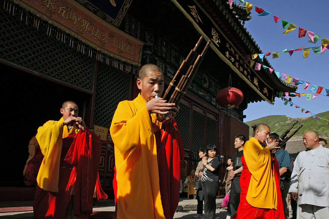 monks in yellow and red robes play bamboo mouth organ and flute, during birthday of Wenshu, Xiantong Monastery, Wutai Shan, Five Terrace Mountain, Buddhist Centre, town of Taihuai, Shanxi province, China, Asia