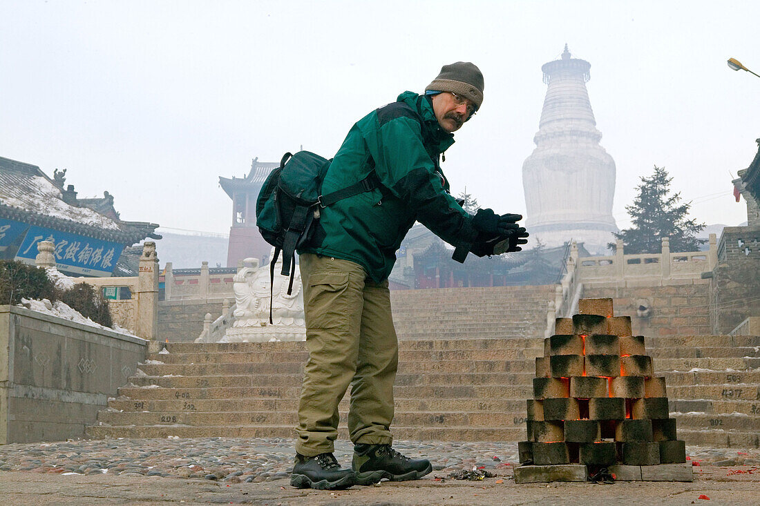 photographer warming hands, minus 20 degree celcius, bonfire, fire, coal, Chinese new year, great white pagoda, Wutai Shan, Five Terrace Mountain, Buddhist centre, town of Taihuai, Shanxi province, China, Asia