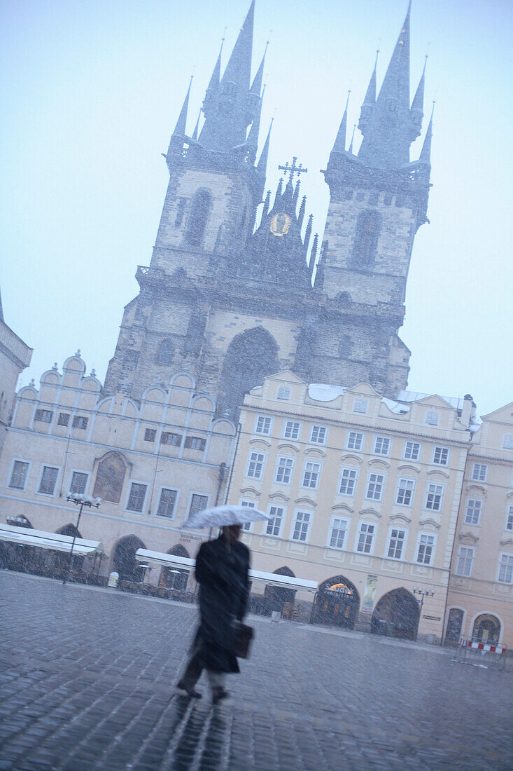 Man walks over the old town square, Staromestske Namesti, with view of Tyn church, Prague, Czech Republic