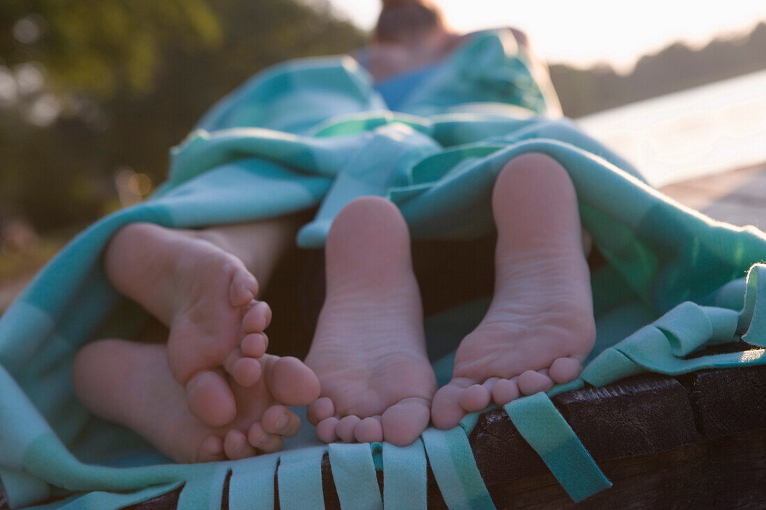 Two young women lying on jetty in blanket