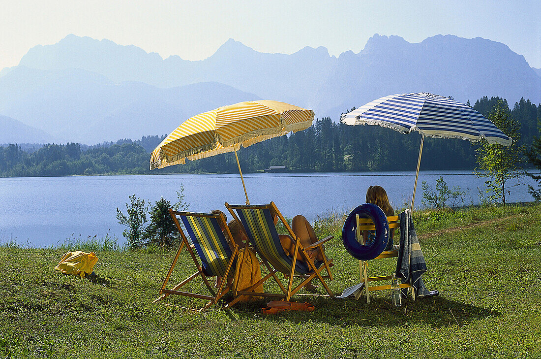 Family sunbathing at lake Barmsee, Krun, Werdenfelser Land, Bavaria, Germany