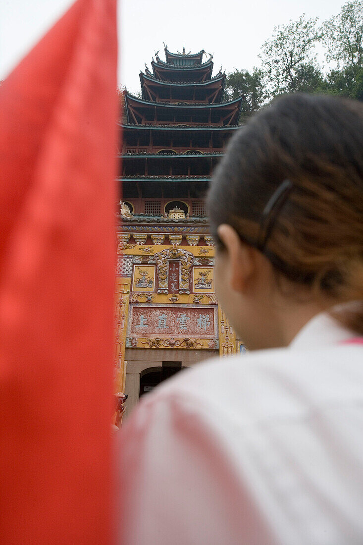 Reiseführerin mit roten Fahne und Pavillon im Hintergrund, Shibaozhai, China
