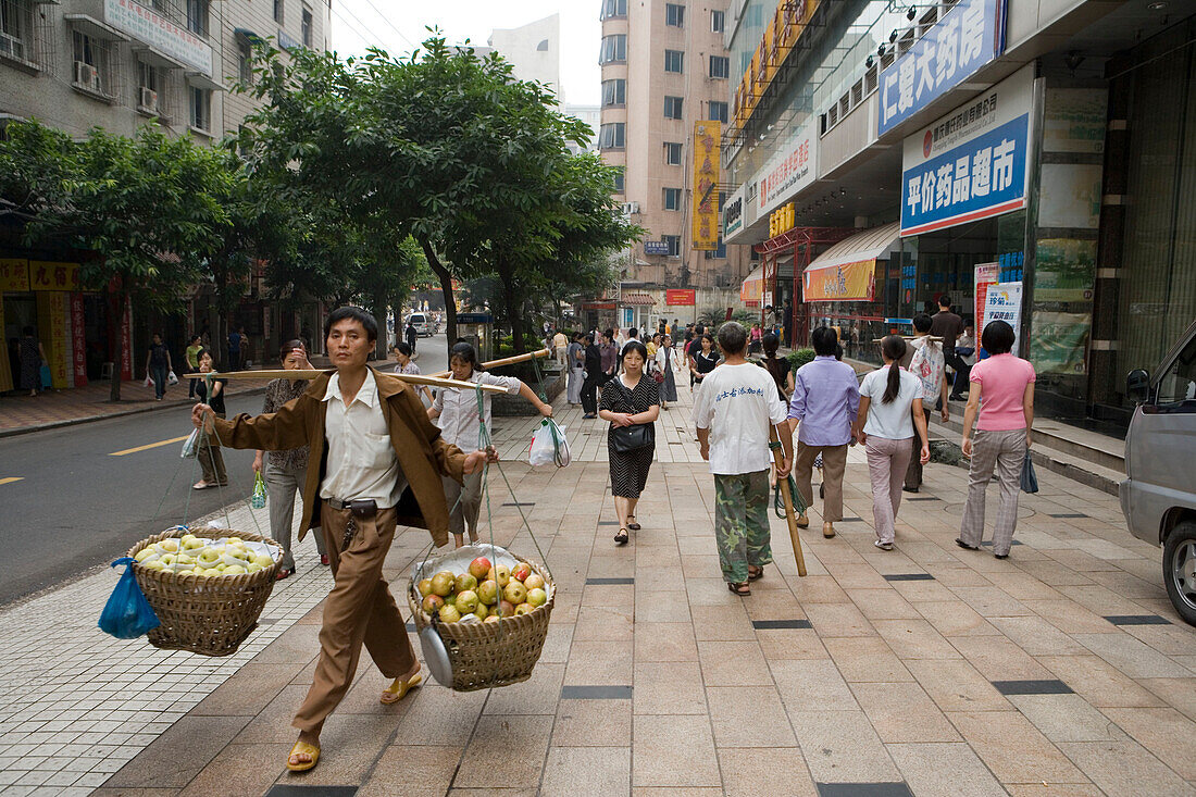 Einheimischer trägt Obstkörbe zum Markt, Chongqing, China