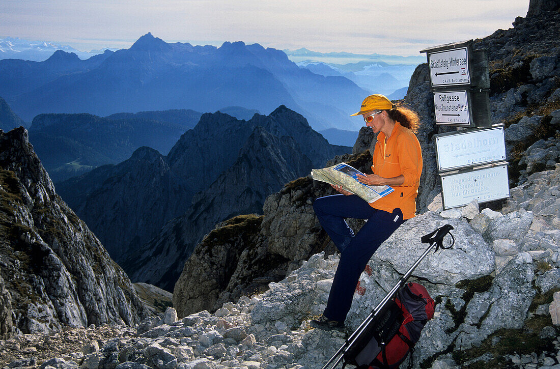 Young woman reading a map, Mayerbergscharte, Reiteralm, Berchtesgaden range, Upper Bavaria, Bavaria, Germany