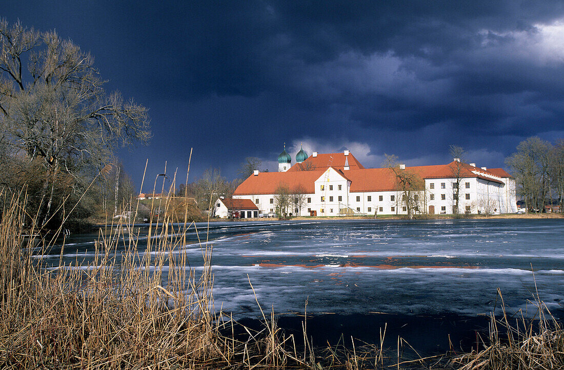 Kloster Seeon mit Gewitterstimmung im Frühjahr, See noch zugefroren, Chiemgau, Oberbayern, Bayern, Deutschland