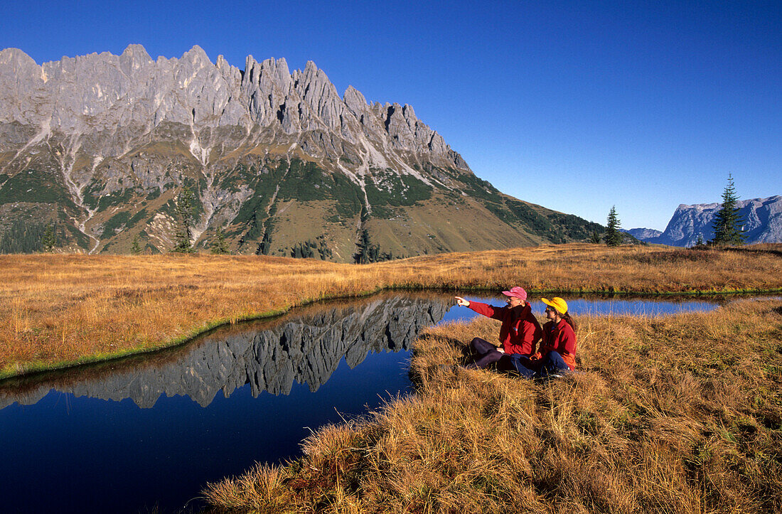 two hikers at lake on Hochkeil, view to Bratschenkopf, Manndlwand, Hochkönig area, Barchtesgaden range, Salzburg, Austria