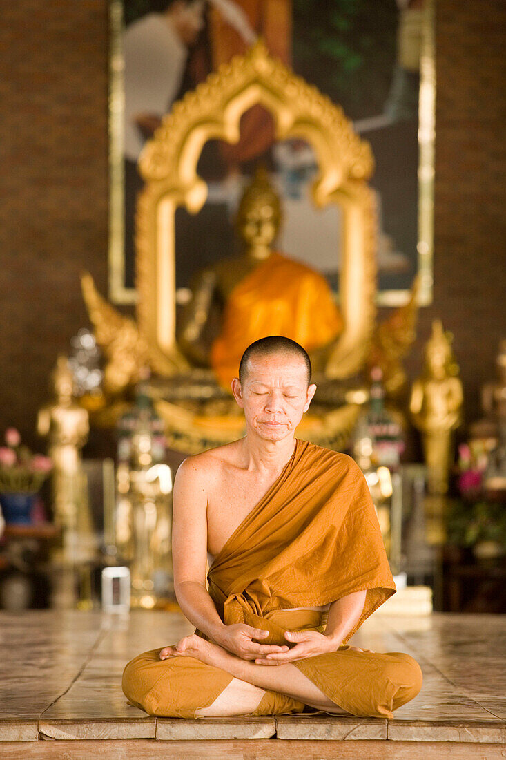 Buddhist monk praying in front of the Golden Jubilee Buddha Image, placed in the Chao Khun Maha Bua Yannasampanno 84-year Campassion Pavilio, Wat Pa Luangta Bua Yannasampanno Forest Monastery, Tiger Temple, Kanchanaburi, Thailand