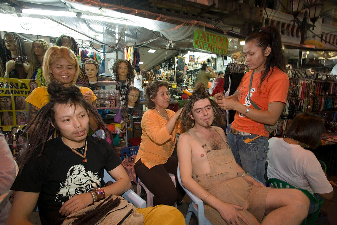 Tourist getting dreadlocks, takes up to 4 hours at a hairdressing stand at Th Khao San Road in the evening, Banglamphu, Bangkok, Thailand