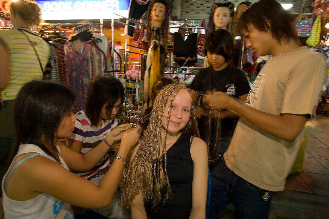 Female tourist getting al lot of afro braids, takes up to 4 hours at a hairdressing stand at Th Khao San Road in the evening, Banglamphu, Bangkok, Thailand