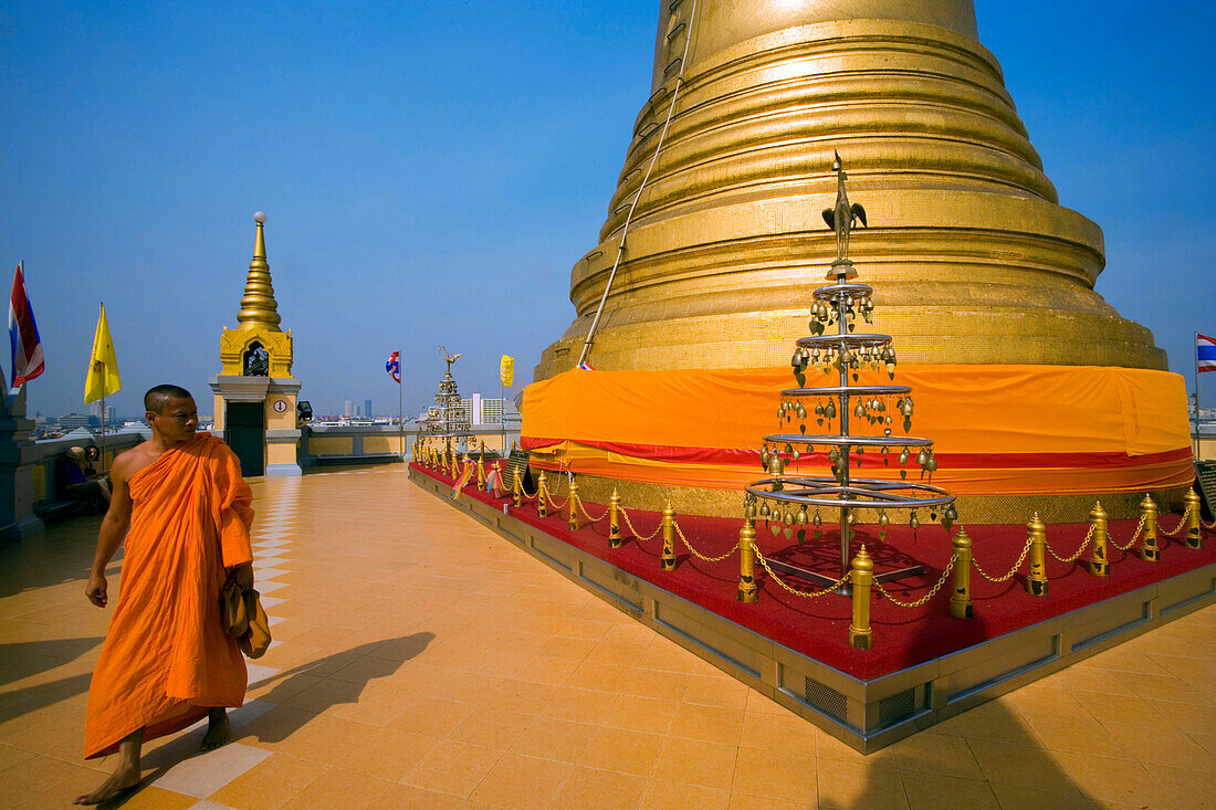 Monk visiting gilded Chedi, housed a Buddha relic of the Wat Saket on the Golden Mount, Bangkok, Thailand