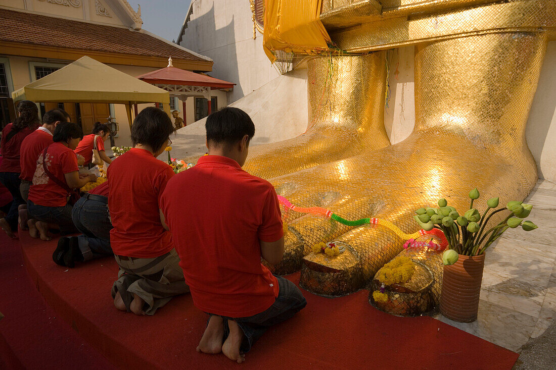 People praying in front of the gilded Buddha statue, 32 m high, Wat Intharawihan, Banglamphu, Bangkok, Thailand