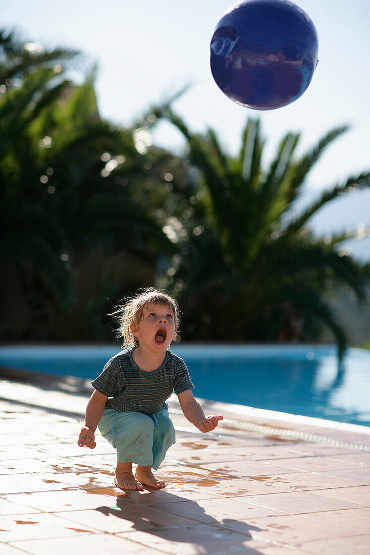 Boy playing with ball, poolside ,bay of Porto Vecchio, Southern Corse, France