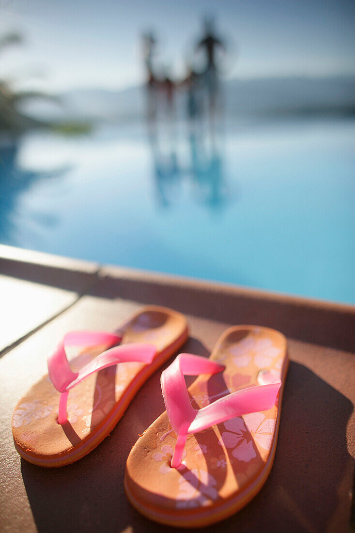 Family on poolside, focus on flip flops in foreground, Bay of Porto Vecchio, Southern  Corse, France