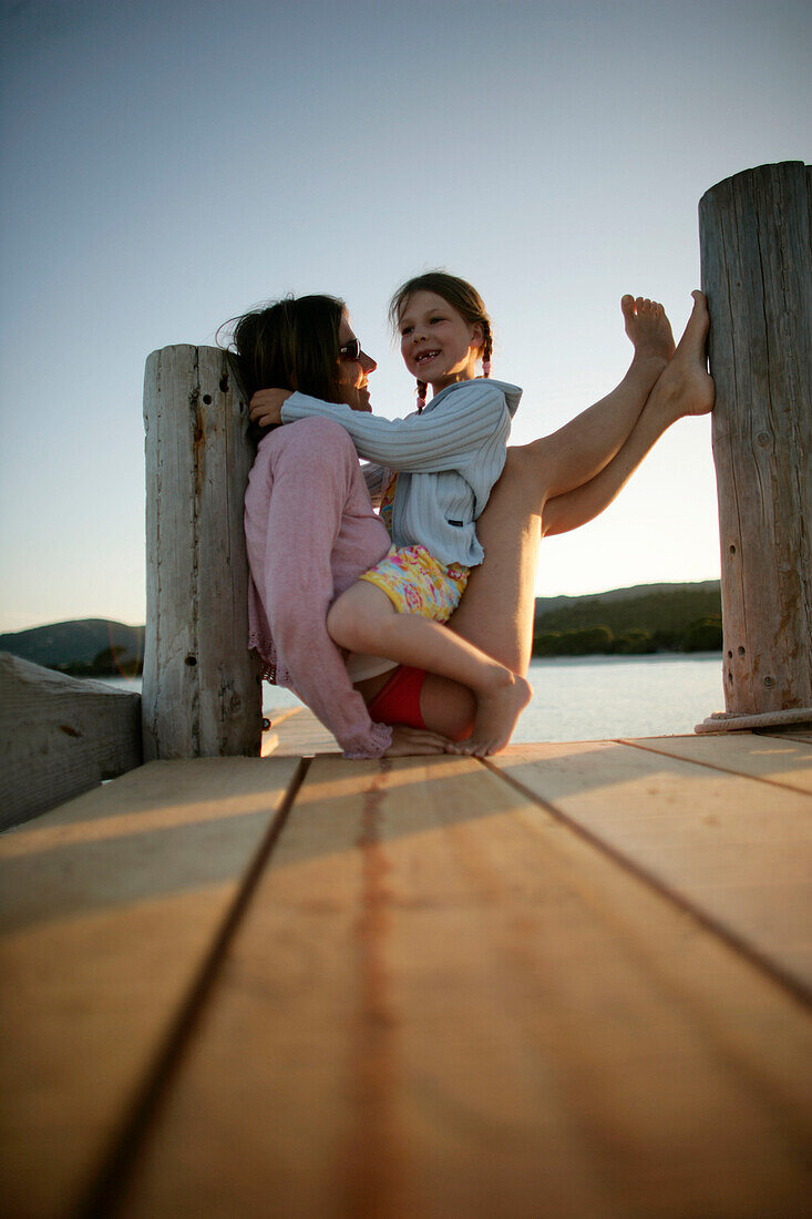 Mutter und Tochter sitzen auf Steg, Santa Giulia, Südkorsika, Frankreich