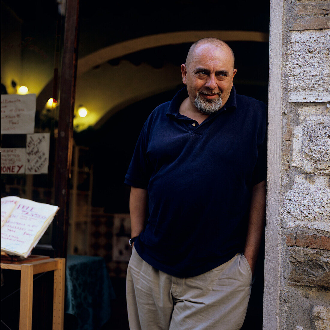 Wine merchant standing at the entrance of his wine store, Montepulciano, Tuscany, Italy