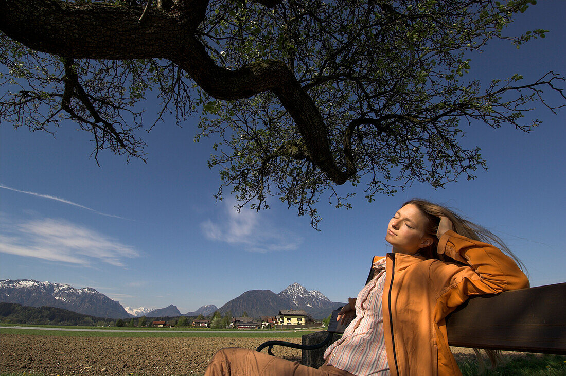 Young woman sitting on a bench enjoying the sunshine, Wals-Siezenheim Salzburg, Austria