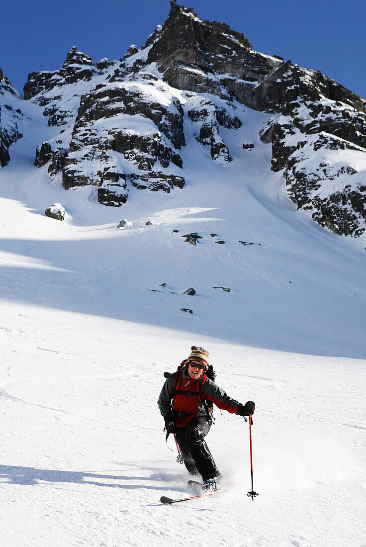 Eine junge Frau fährt mit Telemark Skis einen weiten Hang hinunter. Rila Gebirge, Bulgarien, Europa