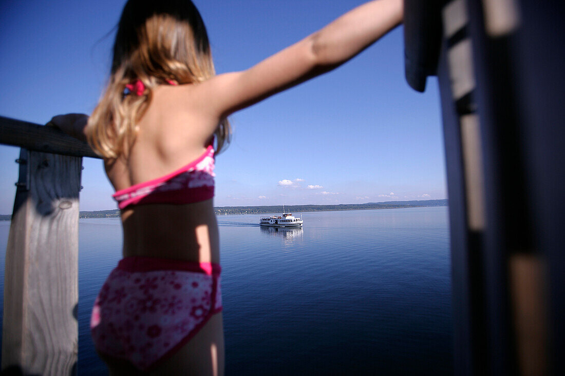 Girl about to jump into the lake from a wooden diving platform, steamboat in the background, Utting, Ammersee,  Bavaria, Germany