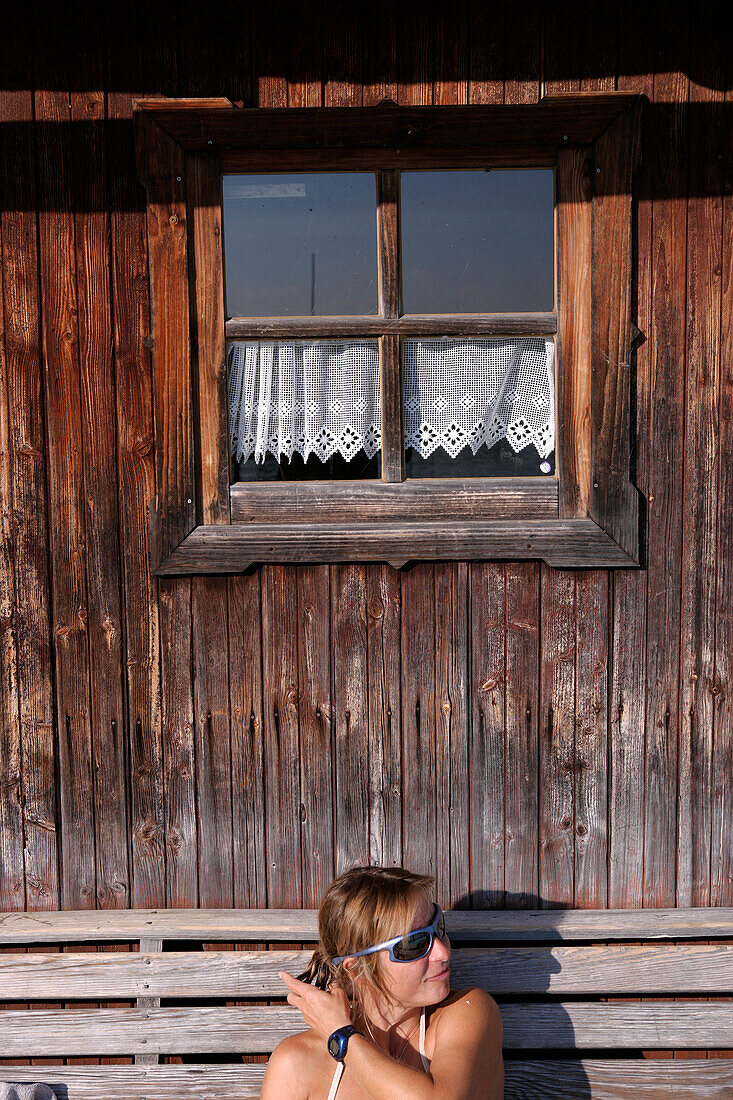 Eine Frau sitzt beim Bootshaus, Utting, Ammersee, Bayern, Deutschland