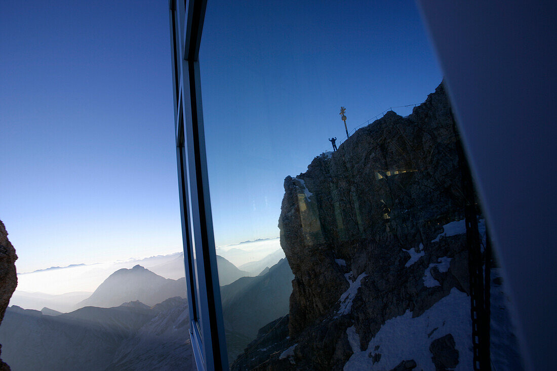 Mann am Zugspitzgipfel im Morgenlicht, Spiegelung im Fenster, Bayern, Deutschland