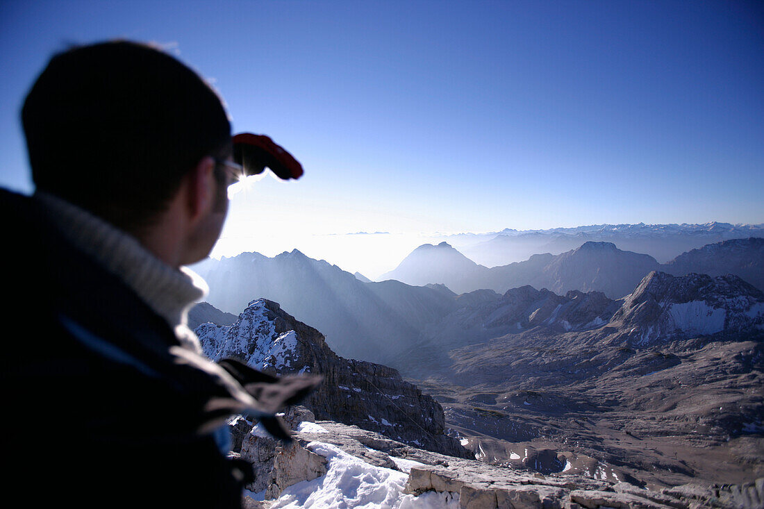 Mann am Zugspitzgipfel im Morgenlicht, Blick über Reintal, Bayern, Deutschland