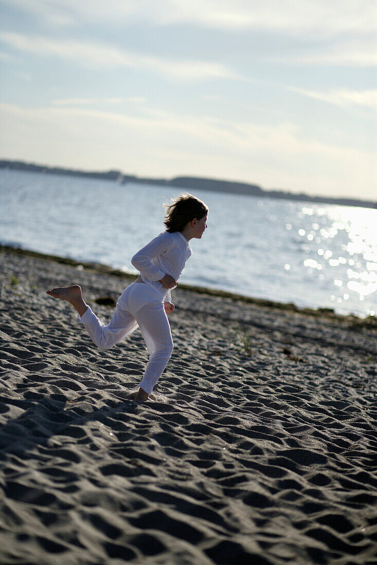 Girl running over sandy beach at Baltic Sea, Travemuende Bay, Schleswig-Holstein, Germany