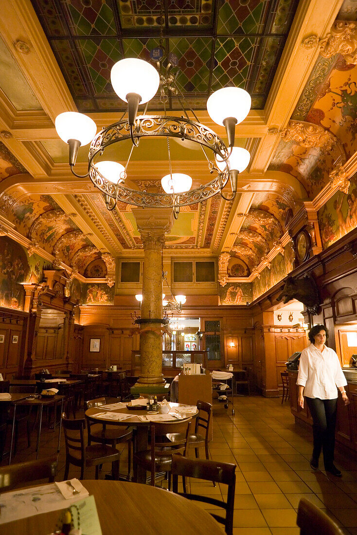 Woman walking through restaurant Bierhalle Kropf (Beer Hall Kropf) with a nice decorated Art Nouveau ceiling, Zurich, Canton Zurich, Switzerland