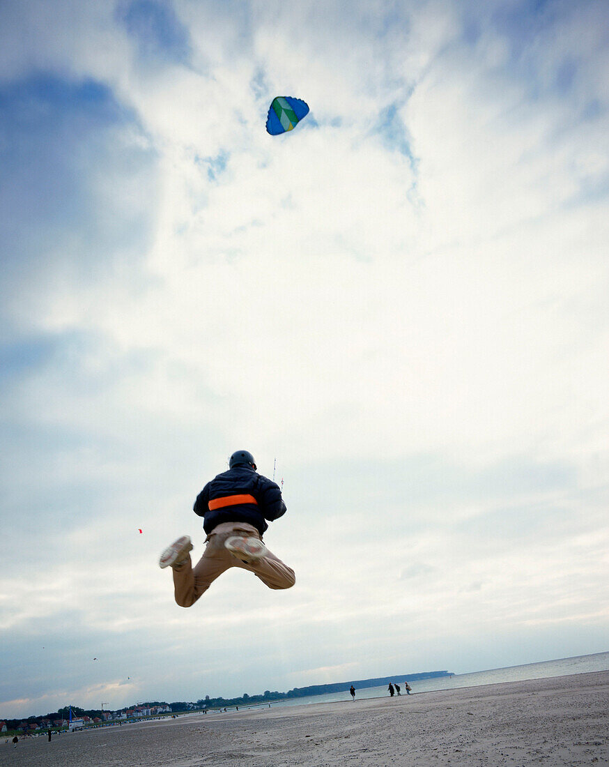 Young man with nasa wing stunt kite, beach of Warnemuende, Mecklenburg-Western Pomerania, Germany