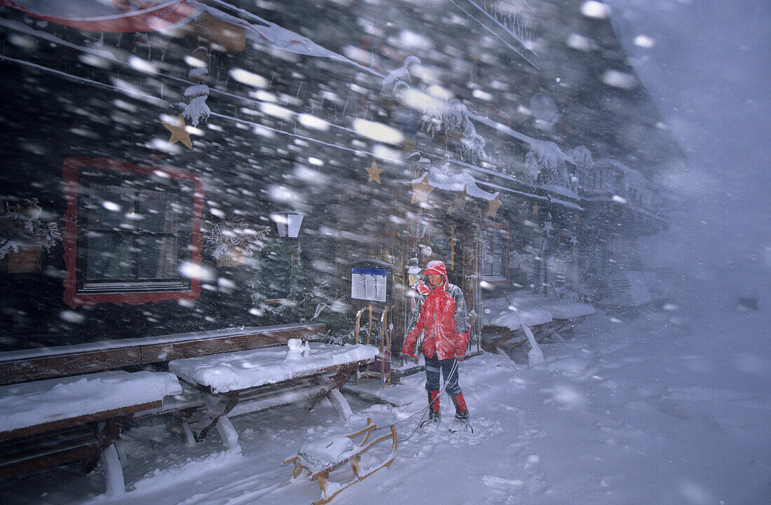 Rodler im Schneesturm vor dem Spielberghaus, Saalbach, Salzburg, Österreich