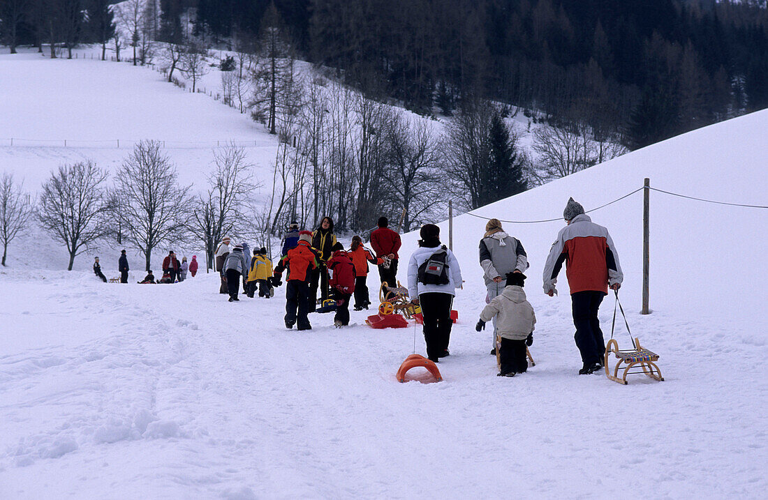 Families hiking on toboggan-run towards Kohlschnait hut, Bruck, Salzburg, Austria