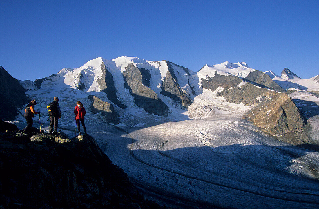 Three alpinists enjoying view to mount Piz Palue and glacier of Pers, Bernina, Upper Engadin, Grisons, Switzerland