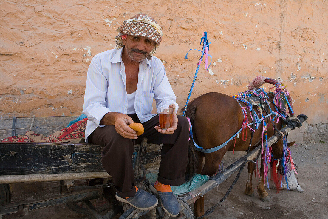 Man with horse carriage enjoying tea and donut break, Dikili, Turkey
