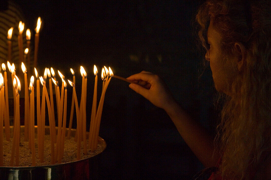 Person lighting candles in a cave of the monastery of the Apocalypse, Patmos, Dodecanese Islands, Greece
