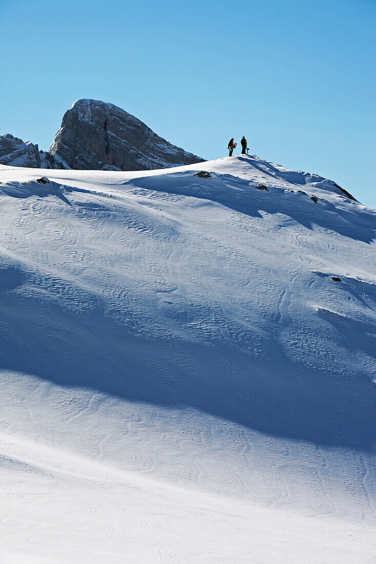 Zwei Männer tragen ihre Snowboards auf den Gipfel eines kleinen Berges, Appenzell, St. Gallen, Toggenburg, Ostschweiz, Schweiz, Alpen, Europa